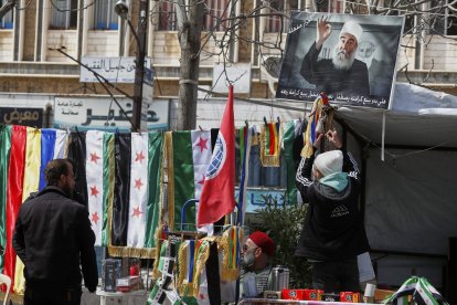 Un joven druso cuelga la imagen de Hikmat al-Hijri, líder espiritual de su comunidad en Siria
