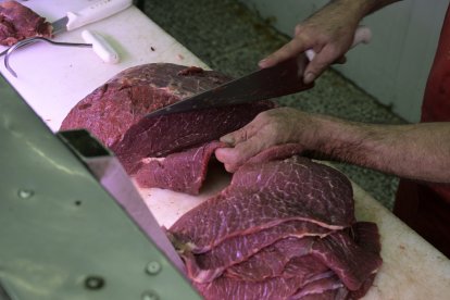 Un carnicero corta un trozo de carne-Imagen de archivo