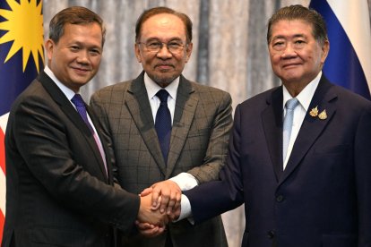 Malaysia's Prime Minister Anwar Ibrahim (C), Cambodia's Prime Minister Hun Manet (L) and Thailand's acting Prime Minister Phumtham Wechayachai (R) pose for photos as they shake hands following a press conference after talks on a possible ceasefire between Thailand and Cambodia in Putrajaya on July 28, 2025. Thailand and Cambodia began discussing a ceasefire in their festering border dispute on July 28, as the deadly skirmish dragged into a fifth day. (Photo by MOHD RASFAN / POOL / AFP)
