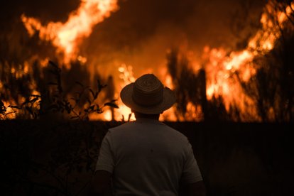 Un hombre observa cómo las llamas arrasan la localidad de Cualedro (España)