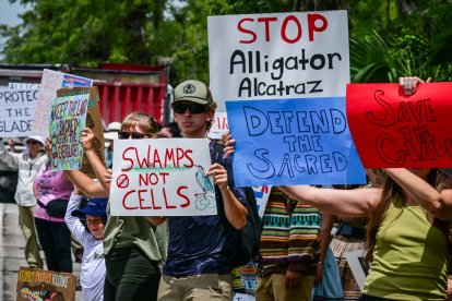 Manifestantes sostienen pancartas mientras protestan contra Alligator Alcatraz