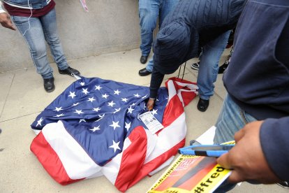 Un manifestante intenta quemar una bandera estadounidense que fue arrancada de un asta frente al Ayuntamiento de Baltimore el sábado 25 de abril de 2015, mientras continúan las protestas tras la muerte de Freddie Gray bajo custodia policial.