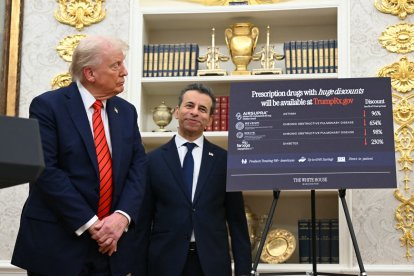 US President Donald Trump looks at a presentation board while he announces a deal on drug pricing as US Commissioner of Food and Drugs Marty Makary looks on at the Oval Office of the White House in Washington, DC, on October 10, 2025. Trump announced a lowering in drug prices with a deal with drug maker AstraZeneca. (Photo by SAUL LOEB / AFP)