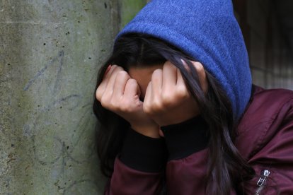 Una adolescente con la cabeza en sus manos llorando