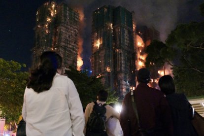 Varias personas observan el incendio en un complejo residencial de Hong Kong