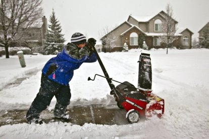 Nicholas Hoye, de 8 años, de Highland, Míchigan, lucha por limpiar la nieve húmeda de la acera, el domingo 12 de diciembre de 2010.