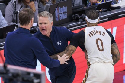 El entrenador jefe de los Golden State Warriors, Steve Kerr, es sujetado por Gary Payton II #0 mientras protesta por una falta no pitada durante el partido de la temporada regular de la NBA 2025 contra los Los Angeles Clippers el lunes 5 de enero de 2026 en el Intuit Dome Arena de Inglewood, California.