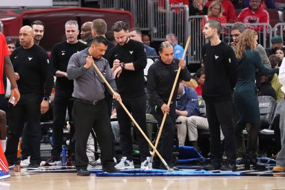 Los empleados del United Center limpian la cancha durante una pausa antes de un partido de baloncesto de la NBA entre los Chicago Bulls y los Miami Heat en Chicago, el jueves 8 de enero de 2026. (AP Photo/Nam Y. Huh)