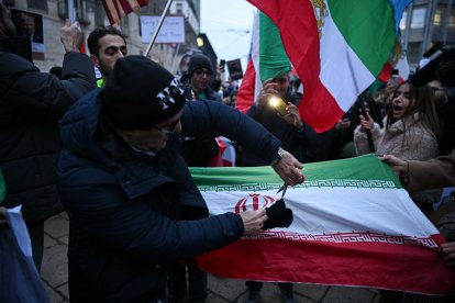 Un manifestante corta la bandera de la República Islámica de Irán