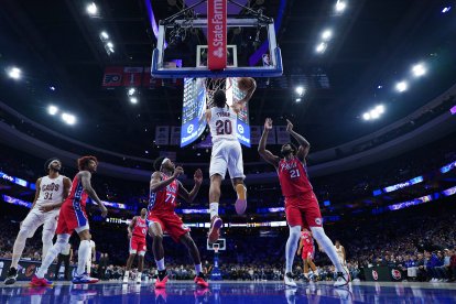 Jaylon Tyson (20), de los Cleveland Cavaliers, realiza un mate entre Joel Embiid (21) y VJ Edgecombe (77), de los Philadelphia 76ers, durante la primera mitad de un partido de baloncesto de la NBA el viernes 16 de enero de 2026 en Filadelfia.