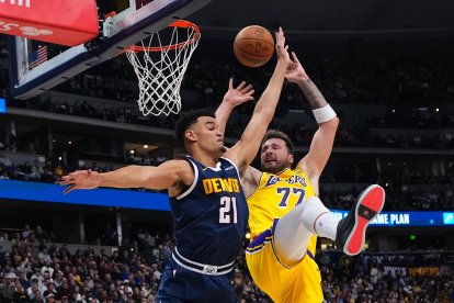 El alero de los Denver Nuggets, Spencer Jones (21), comete una falta sobre el alero de Los Angeles Lakers, Luka Dončić (77), durante la primera mitad de un partido de baloncesto de la NBA el martes 20 de enero de 2026 en Denver.