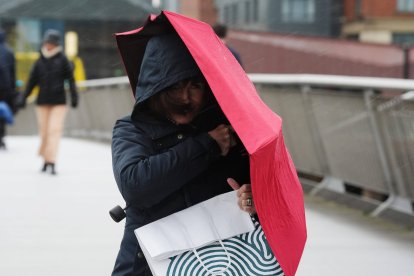 Una persona con un paraguas cruza el puente Sean O'Casey en una tarde lluviosa y ventosa en Dublín, mientras entra en vigor una alerta naranja por lluvia como consecuencia de la tormenta Claudia. Fecha de la fotografía: viernes, 14 de noviembre de 2025.