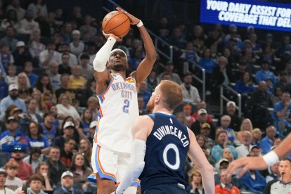 El base de los Oklahoma City Thunder, Shai Gilgeous-Alexander (2), lanza a canasta por encima del base de los Minnesota Timberwolves, Donte DiVincenzo (0), durante la primera mitad de un partido de baloncesto de la NBA, el domingo 15 de marzo de 2026, en Oklahoma City.