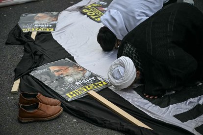 Pro-Iran regime supporters pray on the sidelines of an annual protest, this year a static protest