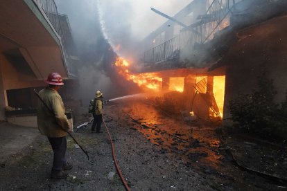 Un bombero del Departamento de Bomberos de Long Beach rocía con agua un edificio de apartamentos en llamas en el incendio de Eaton en Altadena en 2025