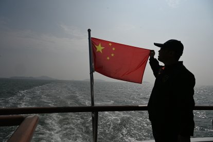 Un hombre sostiene una bandera china sobre un barco