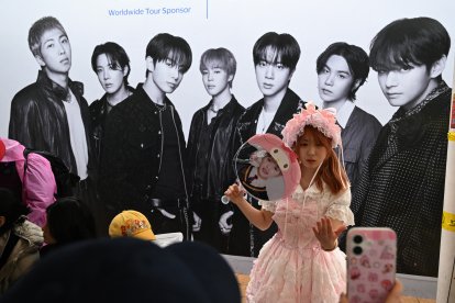 Una chica posa frente a un cartel de la banda de K-pop BTS