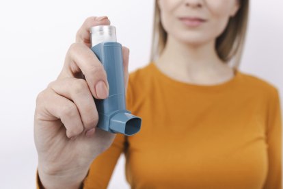 Mujer sosteniendo un inhalador para el asma.