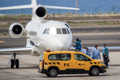 Pasajeros con trajes protectores azules abordan un avión tras ser evacuados del crucero MV Hondius