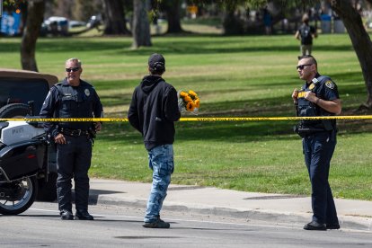 Un hombre lleva flores mientras agentes de la policía de San Diego bloquean el acceso