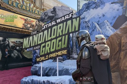 Un cosplayer disfrazado de mandaloriano junto a Grogu en el estreno mundial de "Star Wars: The Mandalorian and Grogu"