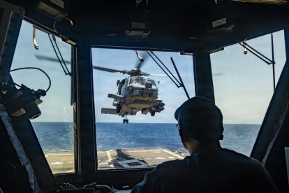 Un marinero estadounidense observa cómo un MH-60R Sea Hawk, adscrito al Escuadrón de Ataque Marítimo en Helicóptero (HSM) 51, despega de la cubierta de vuelo del destructor lanzamisiles de la clase Arleigh Burke USS Rafael Peralta (DDG 115) mientras patrulla el mar Arábigo para hacer cumplir un bloqueo marítimo contra los buques que entran o salen de los puertos y zonas costeras iraníes, el 12 de mayo de 2026. El Rafael Peralta está desplegado en la zona de operaciones de la 5.ª Flota de EE. UU. para apoyar la seguridad y la estabilidad marítimas en Oriente Medio. (Foto de la Armada de EE. UU.)