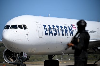 Un avión estadounidense carretea en el aeropuerto Simón Bolívar de Maiquetía. En primer plano, un funcionario de la Policía Nacional Bolivariana.