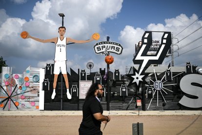 Un hombre camina junto a una escultura que representa a Victor Wembanyama