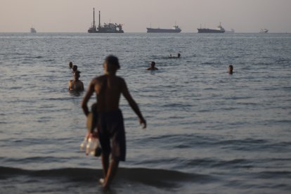 Embarcaciones de carga y comerciales ancladas en el Estrecho de Ormuz, mientras los residentes de Bandar Abbas se entretienen en el agua.