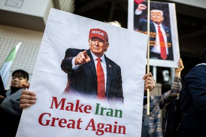 Demonstrators hold placards of US President Donald Trump with text that reads "Make Iran Great Again" during a rally supporting political change near the Iranian embassy in Tokyo on March 17, 2026. (Photo by Philip FONG / AFP)