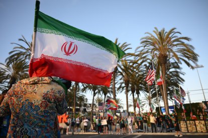 Un hombre sostiene una bandera iraní frente a personas que portan banderas de otros países.