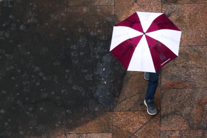 Una persona camina con una sombrilla bajo la lluvia (Archivo)