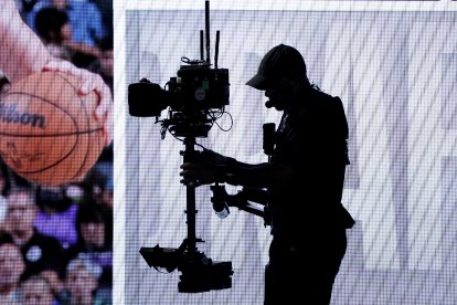 La silueta de un operador de cámara se recorta contra la pantalla del escenario durante la primera ronda de la 78.ª edición del draft anual de la NBA, celebrado en el Barclays Center de Brooklyn el 26 de junio de 2024.