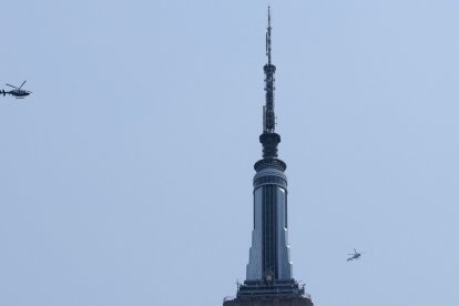 Two helicopters fly near the Empire State Building in New York on July 1, 2026. Two people climbed to the top of the Empire State Building on July 1 and unfurled a banner appearing to read "when the power of love beats the love of power the world knows peace," video published by US media showed. (Photo by TIMOTHY A. CLARY / AFP)