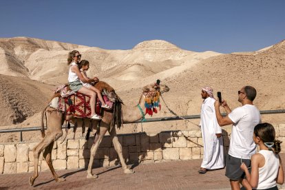 Tourists pose for a picture while riding camels near the sign marking mean sea level (Files)