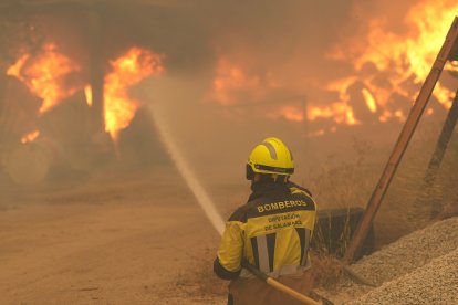 Un bombero rocía con agua neumáticos y barriles en llamas cerca de Ávila, España