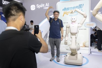 Un visitante y un robot humanoide hacen gestos de corazón mientras posan para fotos durante la Conferencia Mundial de IA 2026, en Shanghái.