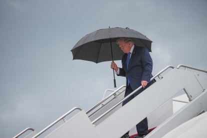 El presidente Donald Trump camina bajo un paraguas al desembarcar del Air Force One en la Base Conjunta Andrews, Maryland, el 2 de agosto de 2026.