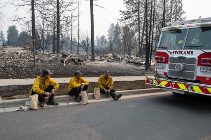 Tres miembros del Cuerpo de Bomberos de Spokane están sentados en el bordillo frente a unas viviendas calcinadas en el barrio de Balboa, en Spokane (Washington), el 2 de agosto de 2026. Los incendios, que avanzaron a gran velocidad, dejaron un rastro de destrucción el domingo en la ciudad de Spokane, situada en el noroeste de Estados Unidos; las autoridades informaron de que cientos de edificios quedaron reducidos a cenizas.