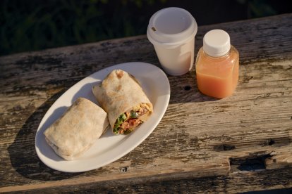 Burritos con café y zumo en una mesa rústica de madera, bajo la cálida luz del sol. California, EEUU