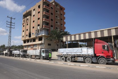 Trucks carrying aid provided by the World Food Programme (WFP) drive on a road in Deir el-Balah