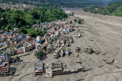 Varias casas parcialmente sumergidas en barro a lo largo de la ribera de un río tras las inundaciones repentinas en Trishuli Bazar, en el distrito de Nuwakot.