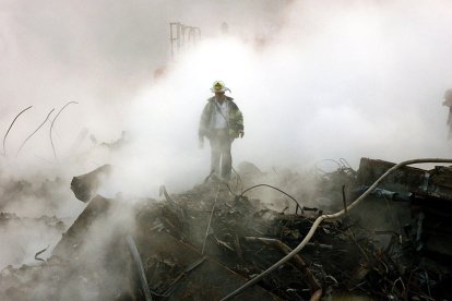 Un bombero camina entre los escombros y los restos humeantes del World Trade Center el 11 de octubre de 2001 en Nueva York. Se celebró una ceremonia interreligiosa en la Zona Cero con motivo del primer mes desde los atentados, que se conmemoró con un breve servicio religioso y un minuto de silencio a las 8:48 de la mañana.