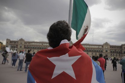 Una persona con una bandera cubana frente a la bandera de México (Archivo)