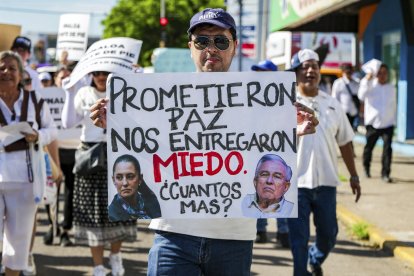 Un manifestante sostiene una pancarta que dice