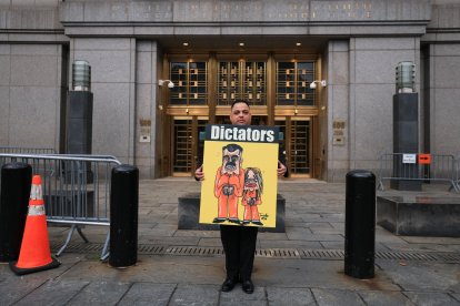 Un manifestante sostiene un cartel con una ilustración del derrocado presidente venezolano Nicolás Maduro y su esposa Cilia Flores, frente al tribunal federal donde tienen lugar las audiencias previas al juicio.