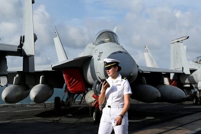 Una efectivo de la Armada estadounidense se encuentra junto a un avión en la cubierta del portaaviones USS George Washington.