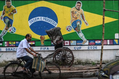 Un ciclista pasa junto a un grafiti con las imágenes del futbolista brasileño Neymar