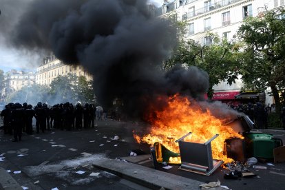 Agentes de policía custodian contenedores de basura y muebles incendiados en la calle durante una manifestación en París