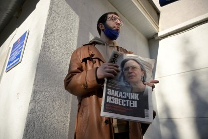 Un hombre sostiene un periódico con la foto de la periodista de investigación Anna Politkovskaya